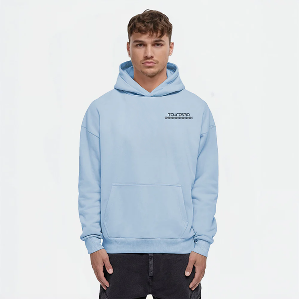 Homme portant un hoodie bleu ciel TOURISMO avec pantalon foncé, fond blanc