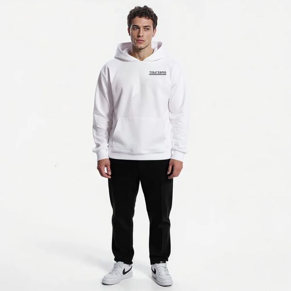 Sweat à capuche blanc homme Tourismo Clothing, avec logo noir brodé et damier discret sur la poitrine. Coupe droite sans cordon, poche kangourou. Porté avec un pantalon noir droit et baskets blanches. Le mannequin se tient debout de face, posture droite, fond uni blanc.