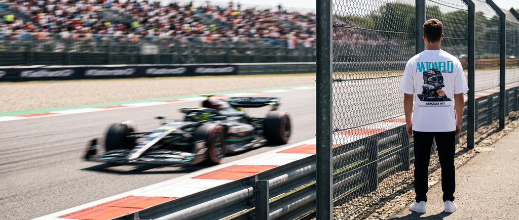 Homme de dos en t-shirt Kimi Antonelli au bord de la piste, une monoplace passe en vitesse derrière lui