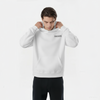 Homme portant un hoodie blanc TOURISMO, enfilant la capuche, regard vers le bas, fond clair