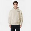 Homme portant un hoodie beige TOURISMO, face à la caméra, mains détendues, fond blanc uni