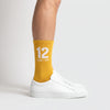 Calcetines Ayrton Senna 12, temporada 1988 amarillo, puestos, vista de perfil con zapatillas blancas