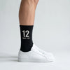 Calcetines Ayrton Senna 12, temporada 1988 negro, puestos, vista de perfil con zapatillas blancas