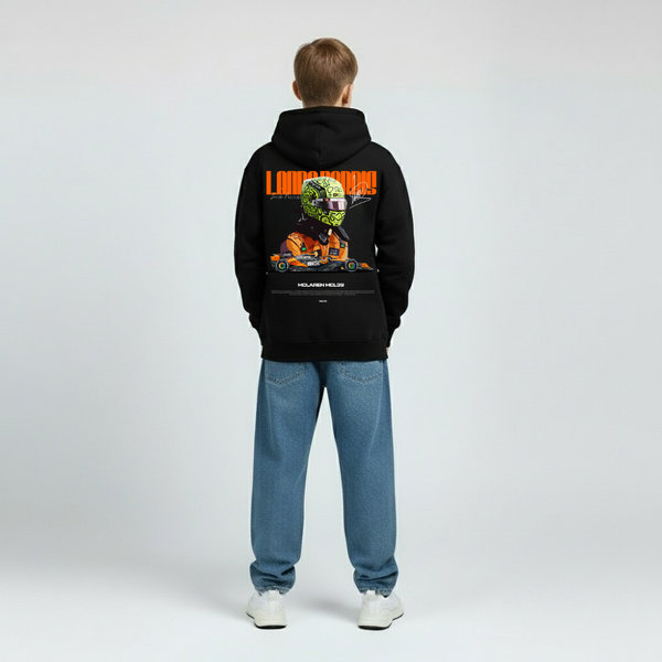 Vue arrière d’un enfant habillé avec le hoodie noir Lando Norris, visuel McLaren en grand au dos avec casque orange et voiture stylisée, capuche sur la tête, bras le long du corps, pantalon bleu droit, fond studio gris clair.