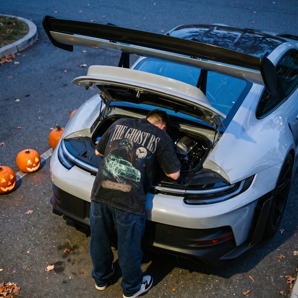 Camiseta The Ghost RS lavada puesta, inclinado sobre el motor trasero de un GT3 RS en la noche de Halloween